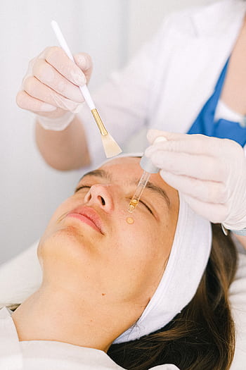 A professional applying serum during a facial treatment in a modern spa setting. HD phone wallpaper