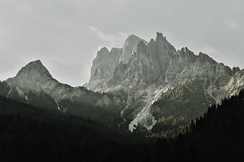 Breathtaking view of rugged mountain peaks with lush forest in foreground, perfect for nature enthusiasts. HD wallpaper
