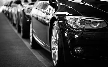Close-up black and white of a luxury car line-up focusing on vehicle headlights. HD wallpaper