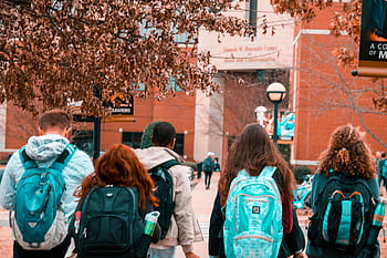 A group of college students with backpacks walking together outdoors on campus. HD wallpaper