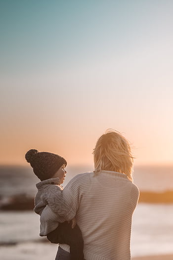 A mother and child share a tender moment on the beach during sunset. HD phone wallpaper
