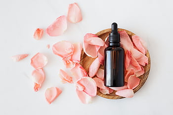 Brown glass dropper bottle on rose petals, perfect for aromatherapy and skincare themes. HD wallpaper
