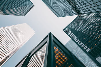 Low angle view of modern skyscrapers with glass facades against a clear sky. HD wallpaper