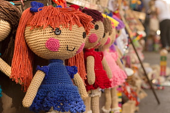 Charming crocheted dolls in bright clothes hang at a market stall. HD wallpaper