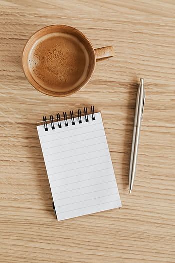 A notebook and coffee cup arranged on a wooden desk, perfect for creative inspiration. HD phone wallpaper