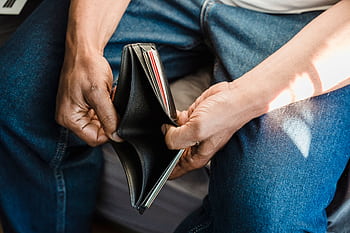 Close-up of a man holding an empty wallet, symbolizing financial crisis and hardship. HD wallpaper