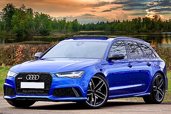 A modern blue Audi RS6 parked by a lake with scenic forest and sky backdrop. HD wallpaper