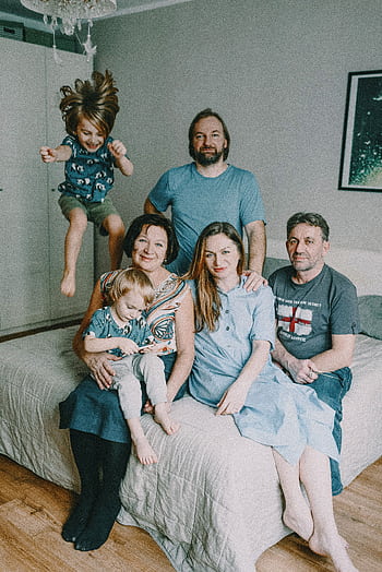 A cheerful multigenerational family posing together in a cozy bedroom setting. HD phone wallpaper
