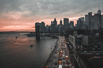 A stunning view of New York City's skyline at dusk featuring the iconic Brooklyn Bridge and bustling waterfront. HD wallpaper