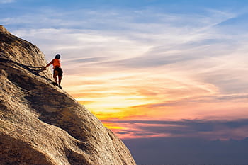 Climber conquers rock face at sunset, embracing the thrill and challenge. HD wallpaper