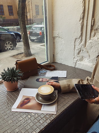 A woman relaxing with coffee and a magazine at a café window seat. HD phone wallpaper