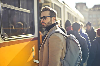 A stylish man with a backpack boards a tram in bustling Budapest, Hungary, during the day. HD wallpaper