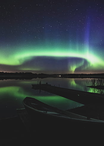 Captivating view of the Northern Lights reflecting over a tranquil lake in Finland. HD phone wallpaper