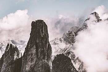 Breathtaking view of dramatic rocky mountain peaks partially obscured by mist and clouds in a serene setting. HD wallpaper