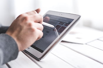 Close-up of a hand using a stylus on a tablet, showcasing digital technology interaction. HD wallpaper