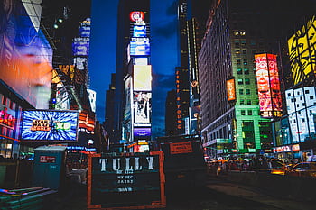 An iconic view of Times Square, New York City, illuminated with colorful lights and billboards at night. HD wallpaper
