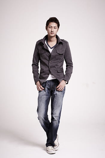 A fashionable young man posing confidently in a studio setting, wearing casual attire. HD phone wallpaper