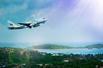 Airplane soaring over Koh Samui island, Thailand, showcasing a vibrant tropical landscape in daylight. HD wallpaper