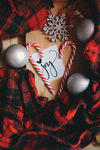 A cozy Christmas flat lay featuring candy canes, ornaments, and plaid scarf creating a joyful holiday mood. HD phone wallpaper