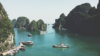 A breathtaking view of Halong Bay with boats navigating through limestone islands. HD wallpaper