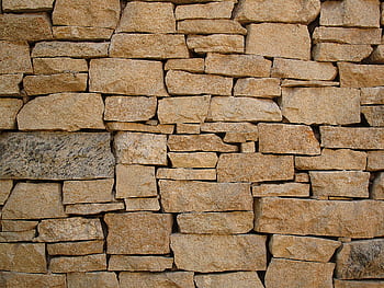 Close-up of a rustic stone wall showcasing natural colors and textures. HD wallpaper