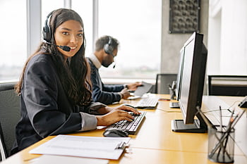 Smiling call center agents in an office providing customer support on computers. HD wallpaper