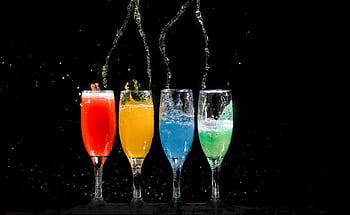Vibrant colored cocktails splashing in glasses against a black background. HD wallpaper