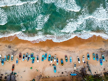 Stunning aerial shot of vibrant boats lined on sandy shores of Arugam Bay, Sri Lanka. HD wallpaper