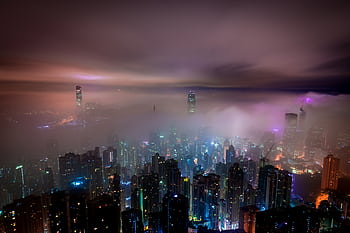 Captivating night view of fog-enshrouded skyscrapers with vibrant city lights. HD wallpaper
