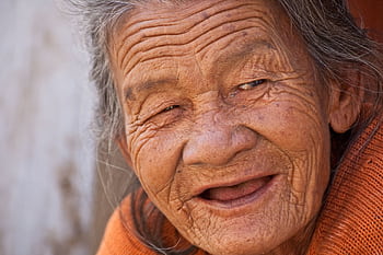 A heartwarming close-up portrait of a smiling elderly woman with deep wrinkles and joyful expression. HD wallpaper