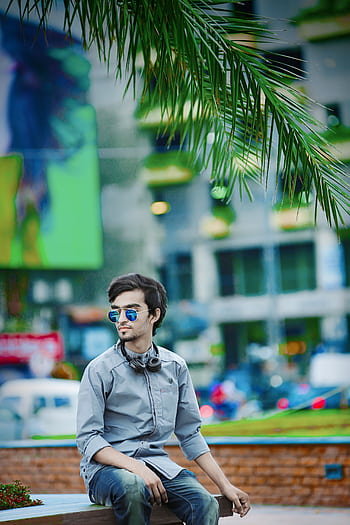 Stylish young man sitting in a vibrant urban park, wearing sunglasses and heads. HD phone wallpaper