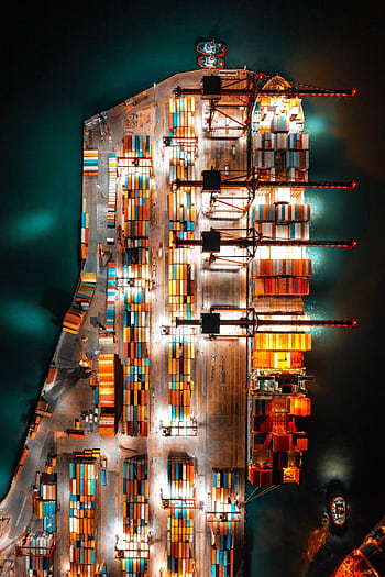 Dramatic aerial view of a busy shipping port with colorful containers and bright lights at night. HD phone wallpaper