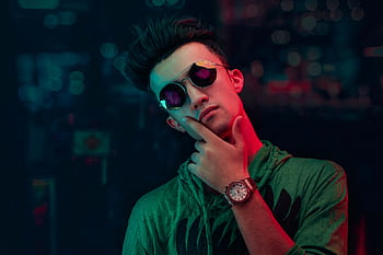 Portrait of a young man in sunglasses and neon lighting, showcasing modern fashion. HD wallpaper