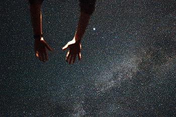 Silhouetted hands reaching towards the starry night sky, capturing a moment of wonder. HD wallpaper