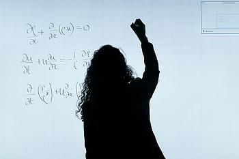 A silhouette of a woman writing mathematical equations on a large whiteboard, representing education and analysis. HD wallpaper