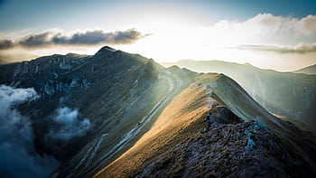 A breathtaking view of the Sibillini Mountains at sunrise with golden sunlight casting over the peaks. HD wallpaper