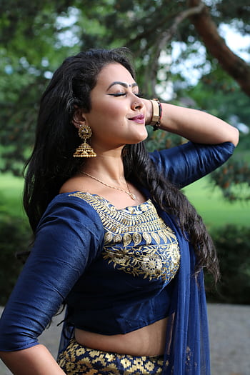 Portrait of a woman in traditional blue and gold attire, posing outdoors. HD phone wallpaper