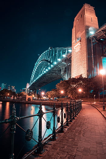 A stunning night view of Sydney Harbour Bridge with glowing lights and water reflections. HD phone wallpaper