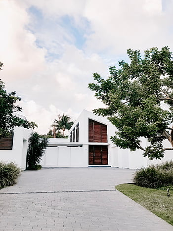 Contemporary minimalist home exterior with lush landscaping and open driveway. HD phone wallpaper