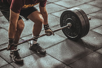 A focused weightlifter prepares to lift a heavy barbell in an indoor gym setting. HD wallpaper