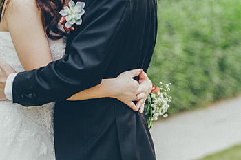 Close-up of a bride and groom hugging in a lush Kowloon garden, capturing wedding romance. HD wallpaper