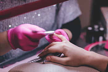 Close-up of a professional manicure session with pink gloves and a nail file in an indoor salon. HD wallpaper
