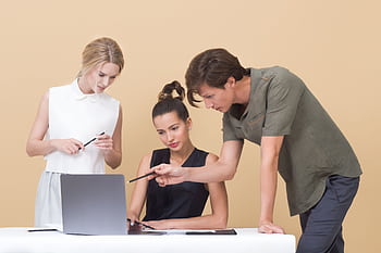 Group of professionals collaborating on a project, discussing ideas around a laptop. HD wallpaper