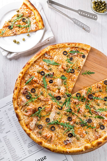 High-angle view of pizza topped with olives, arugula, and cheese. A mouthwatering slice on a plate nearby. HD phone wallpaper