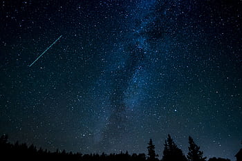 A breathtaking view of the starry night sky with a shooting star streaking across the Milky Way. HD wallpaper