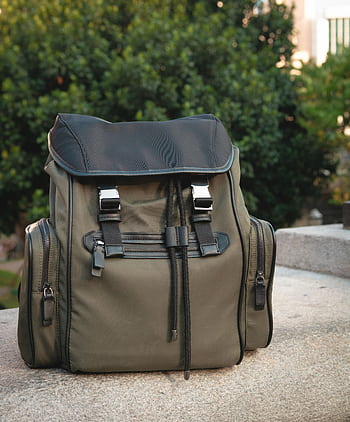 Modern olive green backpack with leather details sitting outdoors on stone. Perfect for travel or fashion look. HD phone wallpaper