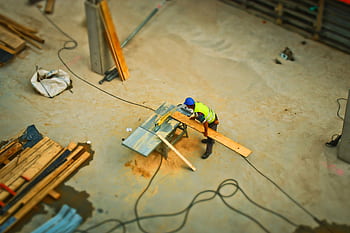 Overhead view of a construction worker using a saw to cut wood at a construction site. HD wallpaper