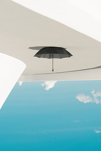 A black umbrella hanging upside down against a clear blue sky, creating a unique and abstract outdoor scene in Brasília, Brazil. HD phone wallpaper