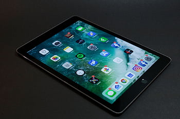 A sleek tablet with various multimedia and social media app icons on display. HD wallpaper