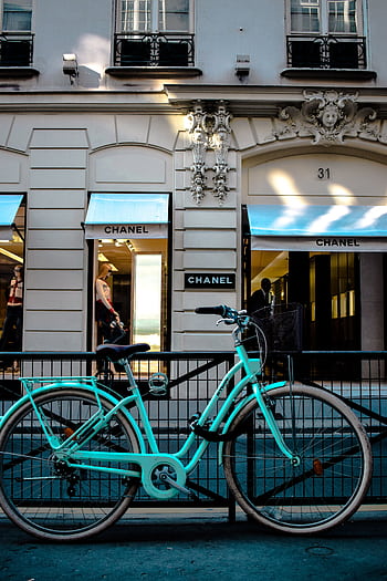 A turquoise bicycle parked in front of a Chanel store in Paris, France. HD phone wallpaper